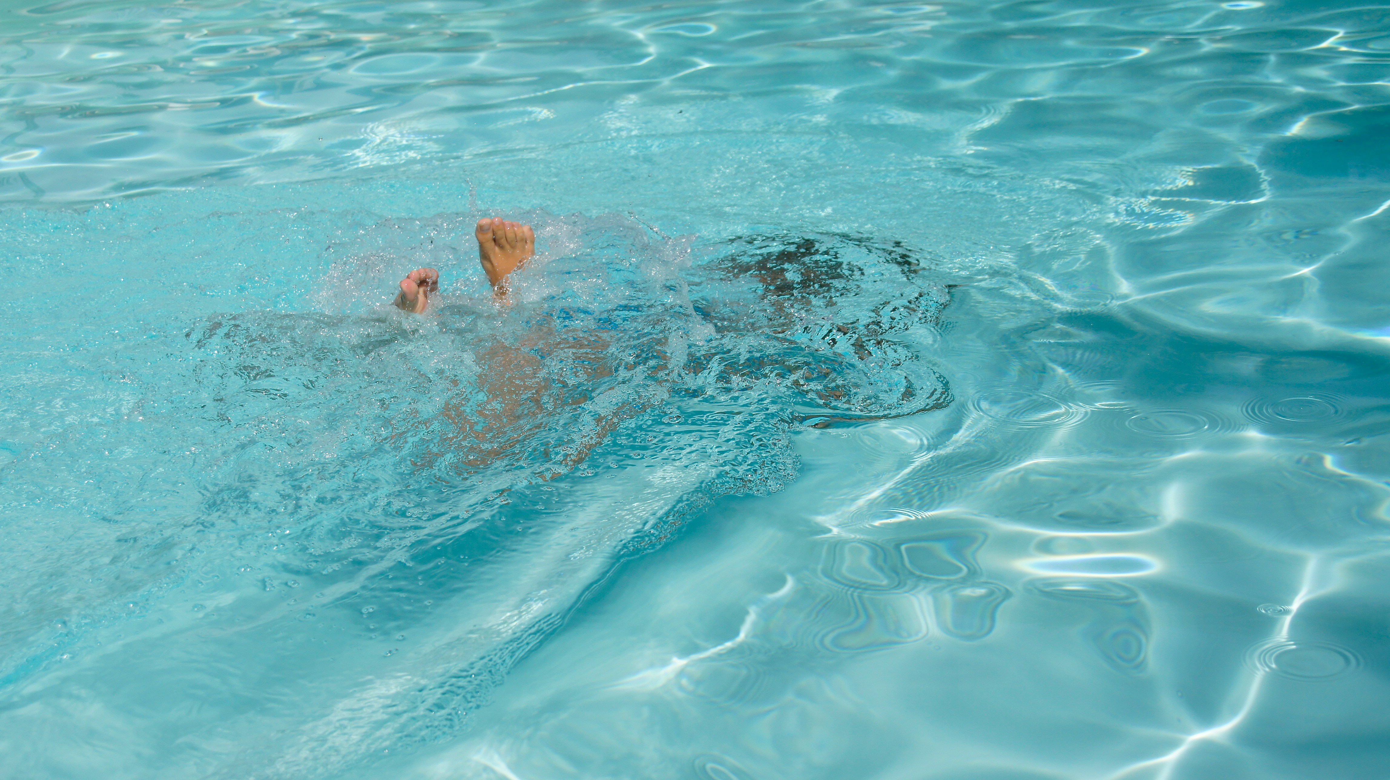 A man swimming in a pool with no shirt on
